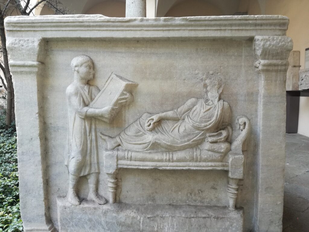 Relief sculpture of person reading to reclining figure